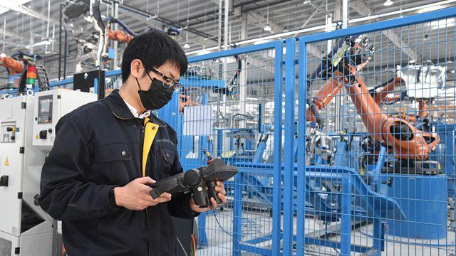 2月10日,工作人员在北京的一家汽车零部件生产企业进行机器人轨迹调整